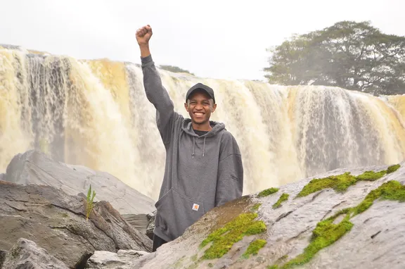 Lewis raising a fist in front of Fourteen Falls